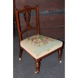 A Victorian low chair with carved pierced back and floral tapestry seat