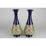 A pair of Royal Doulton blue and gilt pear shaped vases with floral panels, 28cm high