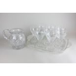 A set of eight cut glass wine glasses, a water jug and a clear and frosted glass tray decorated with