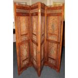 An Indian style hardwood four division room screen with carved floral, star and honeycomb pattern