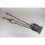 A pair of fireside tongs with a matching shovel, both with ornate brass handles with embossed