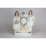 A Staffordshire pottery flat back figure of a man and woman with a doe below a painted clock face,