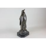 A bronze statue of an Emperor penguin with chick standing on a Christmas pudding, 38cm high