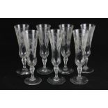 Seven glass champagne flutes with etched grapevine decoration (one with chip to base)