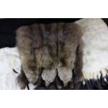 Three various fur stoles, including one with mink heads, three hand muffs and a purse