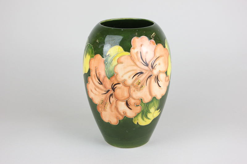 A Moorcroft hibiscus pattern vase, circa 1960, in pink and peach on dark green ground, 18cm high