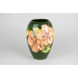 A Moorcroft hibiscus pattern vase, circa 1960, in pink and peach on dark green ground, 18cm high