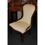 An mahogany framed nursing chair with cream upholstery on curved legs