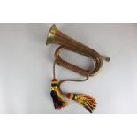 A copper and brass bugle with red, blue and gold braid and tassels