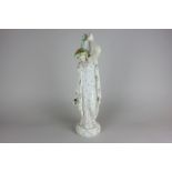 A marbled effect porcelain figure of a classical lady carrying water pitchers, 38cm high