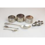 Three various George V silver napkin rings with engraved initials, a teaspoon, two cruet spoons