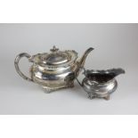 A George V silver teapot, oval shape with raised scroll border, and a matching cream jug, Robert &