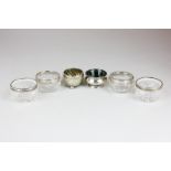 Four early 20th century silver mounted glass salts, a George VI silver salt with green glass liner