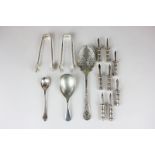 Four pairs of white metal corn spikes, two sugar tongs, a silver plated caddy spoon, mustard spoon