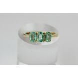 An Emerald three stone ring, claw set with oval cut stones in 18ct gold