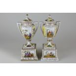 A pair of Vienna porcelain urns, each depicting scenes of lovers, with yellow floral panels (one lid