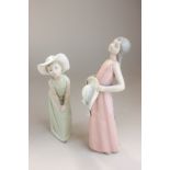 Two Lladro porcelain figures of girls, one in pink sun dress holding a hat, the other in green