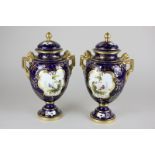 A pair of Coalport porcelain baluster urns with covers, each with a hand painted scene of a bird