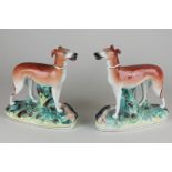 A pair of Staffordshire pottery models of greyhounds standing on oval bases, 18cm, (NC)