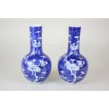 A pair of Japanese blue and white narrow neck porcelain vases, each decorated with cherry blossom,