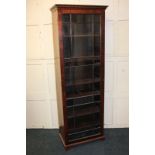 A mahogany bookcase of narrow form with carved detail cornice, single glazed panel door (a/f -