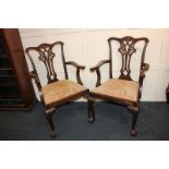 A pair of Chippendale style carved mahogany carver dining chairs with pierced scroll backs and
