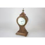 An Edwardian mahogany mantel clock with white enamel dial, in balloon shaped case with brass vase