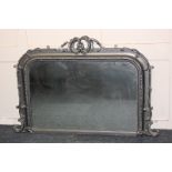 An over mantle mirror with scrolling foliate silver painted frame (a/f) 105cm by 70cm