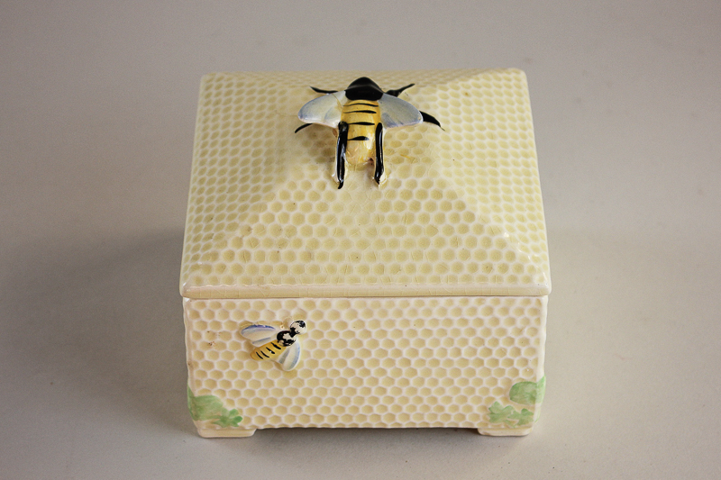 A Crown Devon pottery square honeycomb box and cover with overlaid bee decoration (a/f - wing