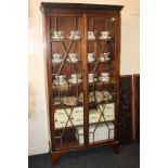 A mahogany bookcase with carved cornice, twin panel glazed doors enclosing five shelves, on