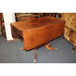 A mahogany Pembroke table with opposing dummy drawer, on pedestal support and quatreform base with