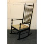 An ebonised spindle back rocking chair with tapestry seat