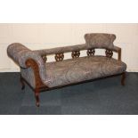 An upholstered chaise longue in William Morris style fabric, with pierced vase shaped supports, on