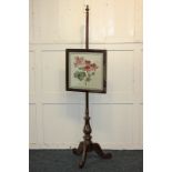 A mahogany adjustable fire screen with glazed woolwork panel, on baluster stem and tripod legs,