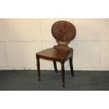 A Victorian mahogany hall chair, with oval back carved with central starburst design and solid seat,