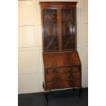 A mahogany bureau bookcase with twin panel glazed doors above drop writing flap enclosing fitted