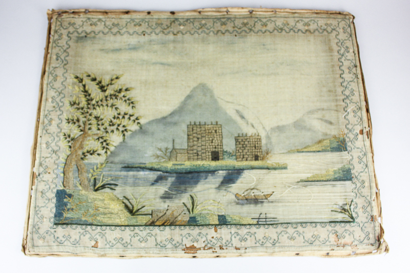 A 19th century needlework panel depicting a castle surrounded by a lake with a rowing boat, 45cm
