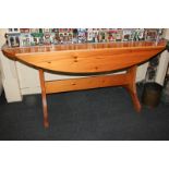 A modern pine oval dining table, with drop flaps on twin end supports with stretchers