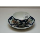 A WORCESTER POLYCHROME TEA BOWL AND SAUCER DECORATED WITH FLOWERS IN RESERVES WITHIN SCALE BLUE