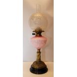 A BRASS OIL LAMP WITH DUPLEX BURNER AND PINK GLASS MOULDED FONT