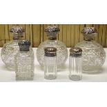 A SET OF THREE LARGE SPHERICAL CUT GLASS SCENT BOTTLES WITH SILVER TOPS ALONG WITH THREE OTHER