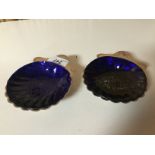 A PAIR OF SILVER SHELL BUTTER DISHES WITH BLUE GLASS LINERS,