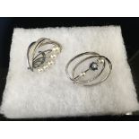 TWO WHITE METAL PEARL BROOCHES ONE SET WITH A SOLITAIRE DIAMOND SURROUNDED BY BLUE STONES