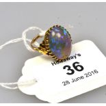 A single stone opal ring, the large oval opal in multiple claw mounts to gold floral shoulders and