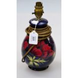 A Moorcroft pottery table lamp, of baluster form, decorated with red and mauve anemone on a deep