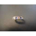 An 18ct yellow and white gold ring with three diamonds and four sapphires in channel setting,