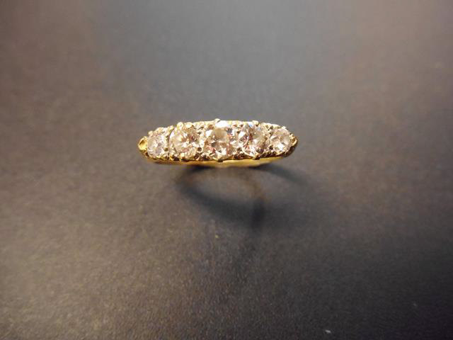 A yellow metal ring with five diamonds of graduating size in scroll setting, size N1/2.