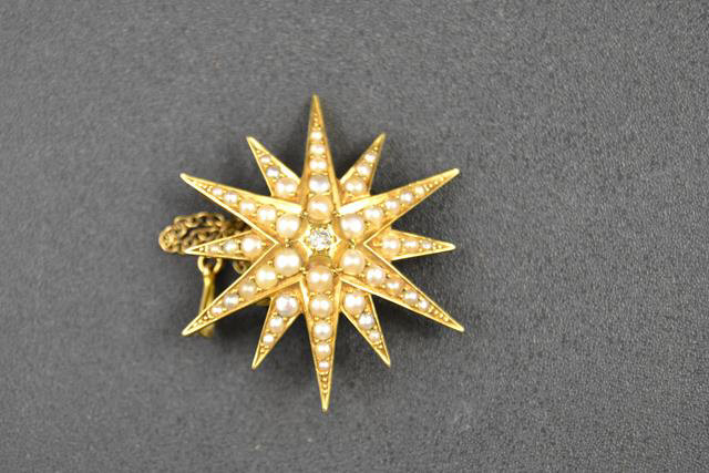 An 18ct gold star brooch/pendant set with central diamond and seed pearls, with safety chain,