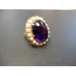 A 9ct gold ring set with oval amethyst surrounded by eighteen pearls, scroll detail to mount,