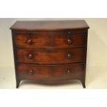 An early 19th century mahogany bow fronted chest, brushing slides, three graduated drawers with